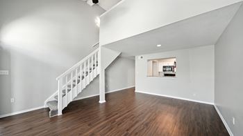 A white staircase with a wooden floor and a small window.